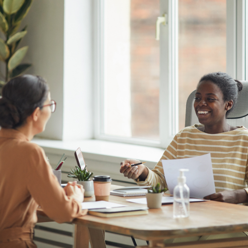 two-female-coworkers-talking-and-smiling
