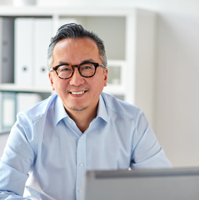 middle-aged-man-smiling-wearing-glasses-using-laptop